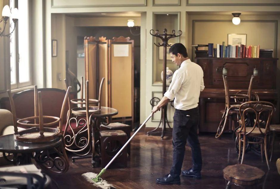 A couple tidying up their living room, organizing furniture and rugs with teamwork.